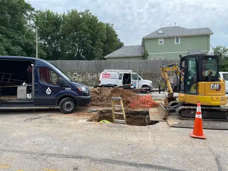 Signs of a Water Line Leak in Kansas City (and What to Do Next) 4 John the Plumber crew with an excavator and open trench at a Kansas City property, the kind of dig needed to reach a broken water line